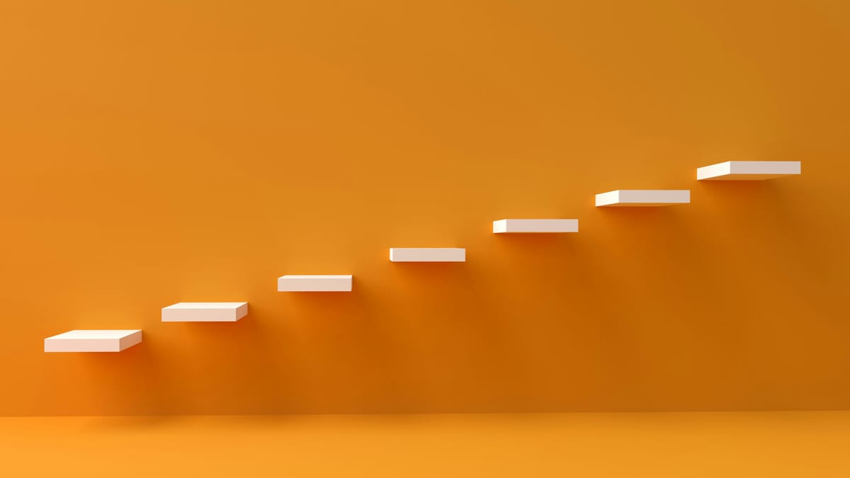 Eine orangefarbene Wand, an der stufenweise aufsteigend weiße Platten montiert sind.